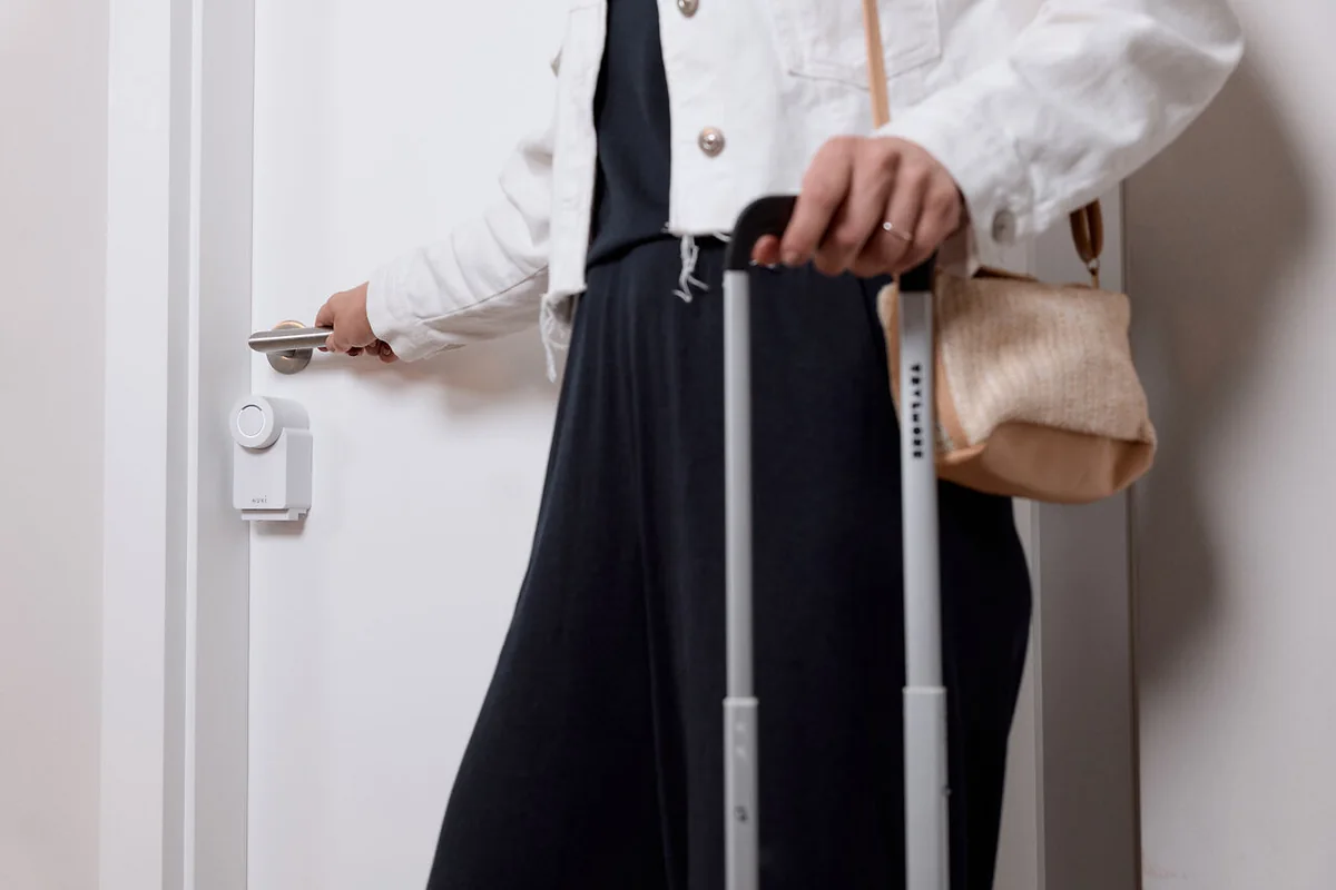 Guest with a suitcase opening an apartment door fitted with a smart lock