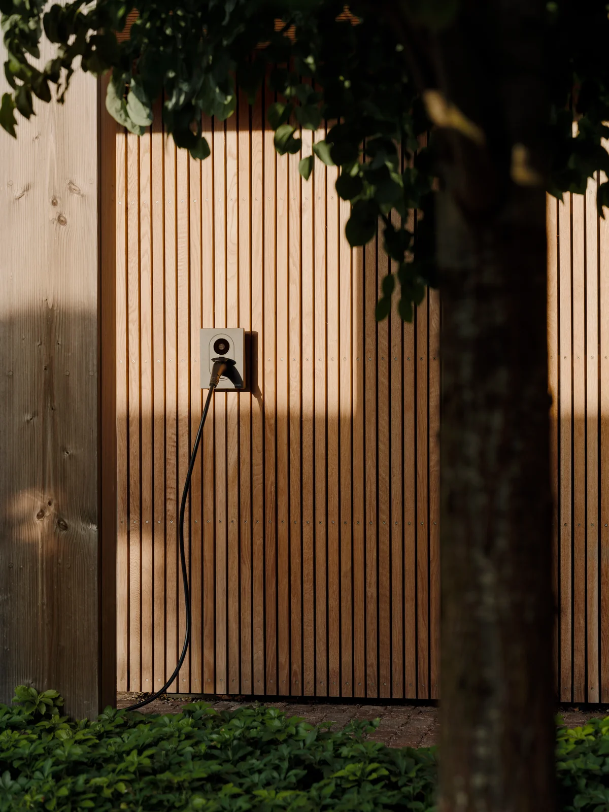 Zaptec Go 2 wall charger on the timber-clad wall of a guest house
